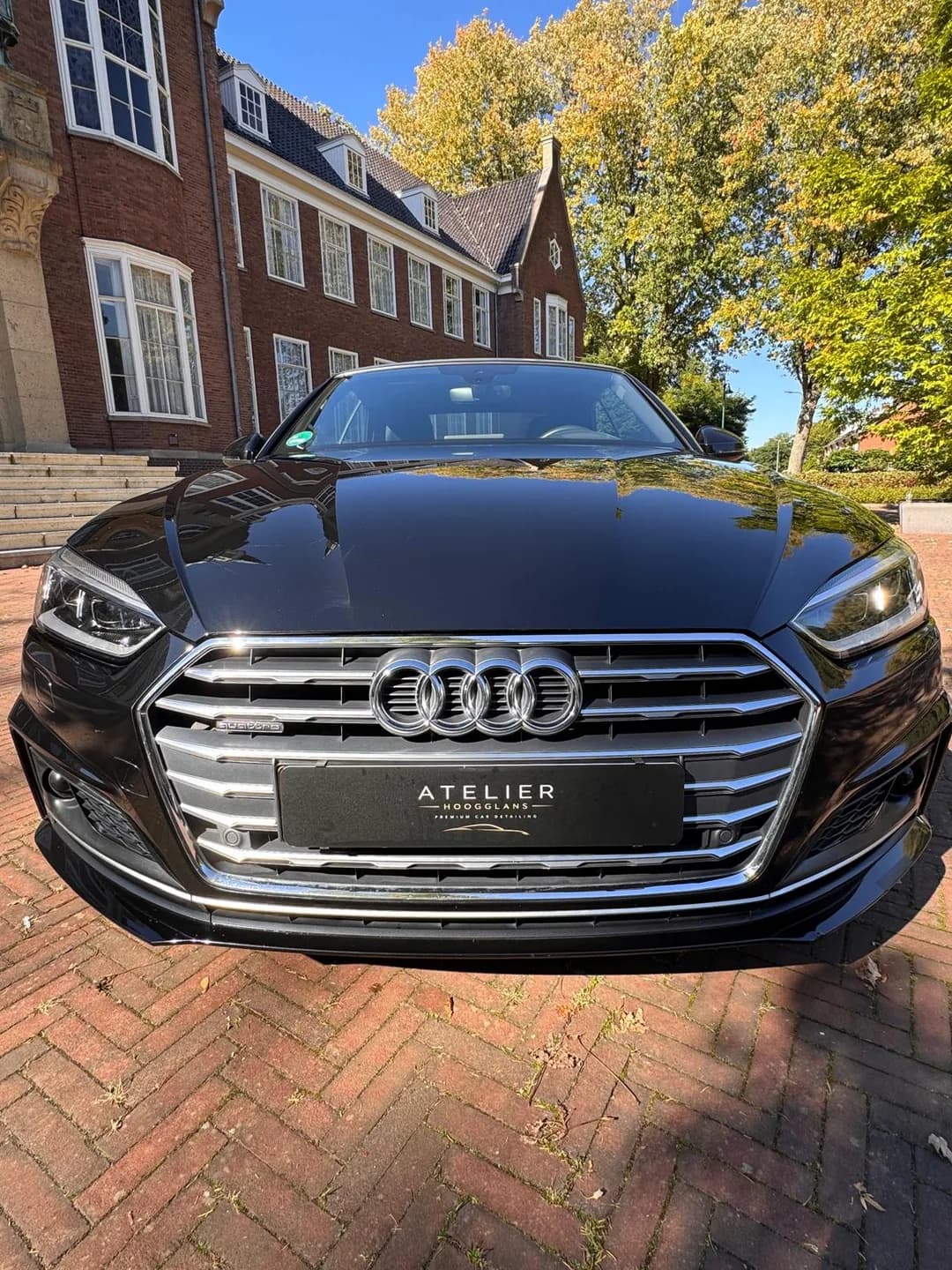 Voorzijde van de zwarte Audi cabriolet met grille en Atelier Hoogglans kentekenafdekking