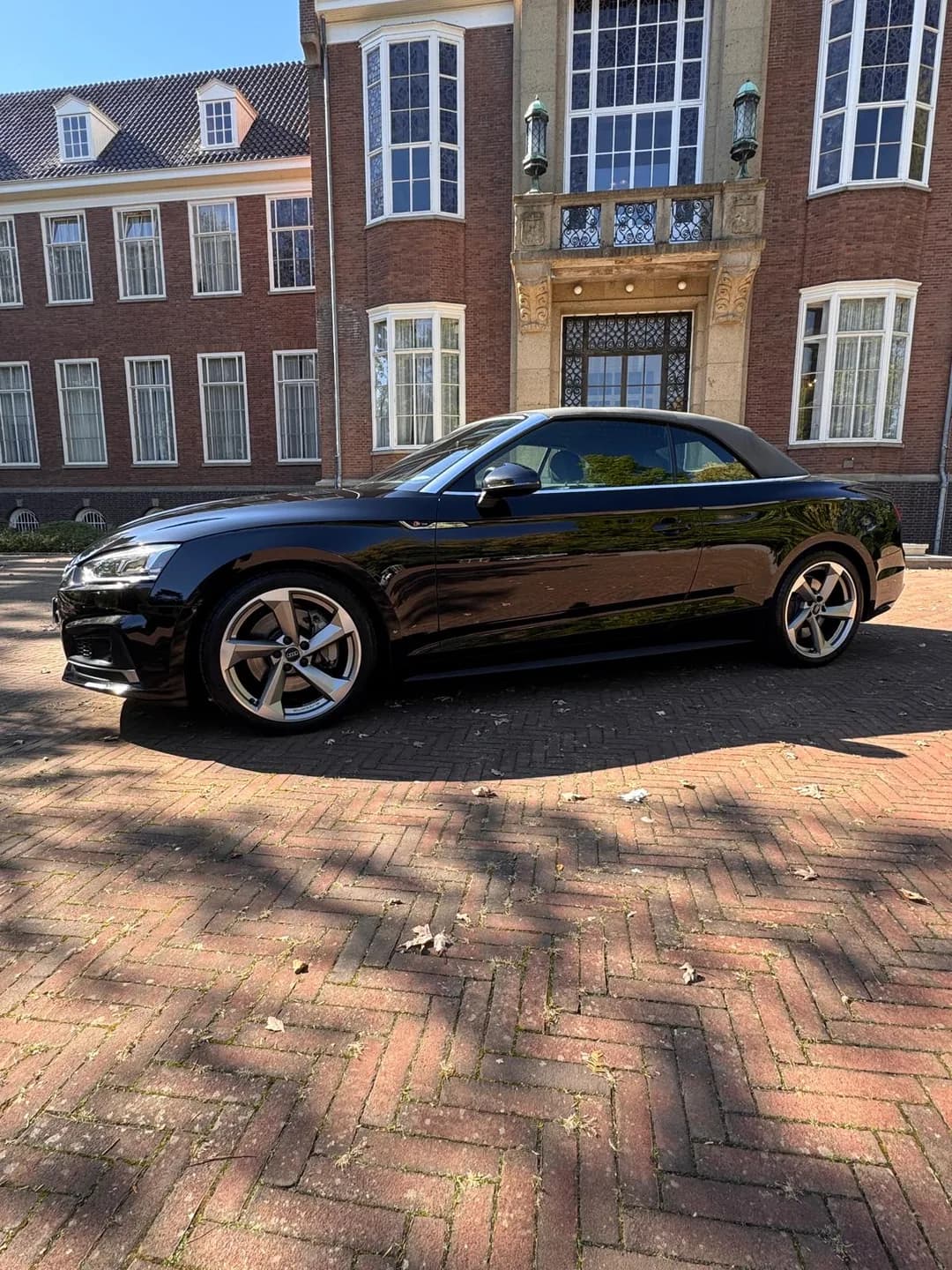 Zwarte Audi cabriolet met gesloten stoffen dak in zijaanzicht bij daglicht