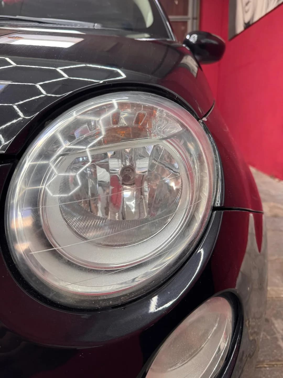 Close-up van de ronde Fiat 500 koplamp onder werkplaatsverlichting