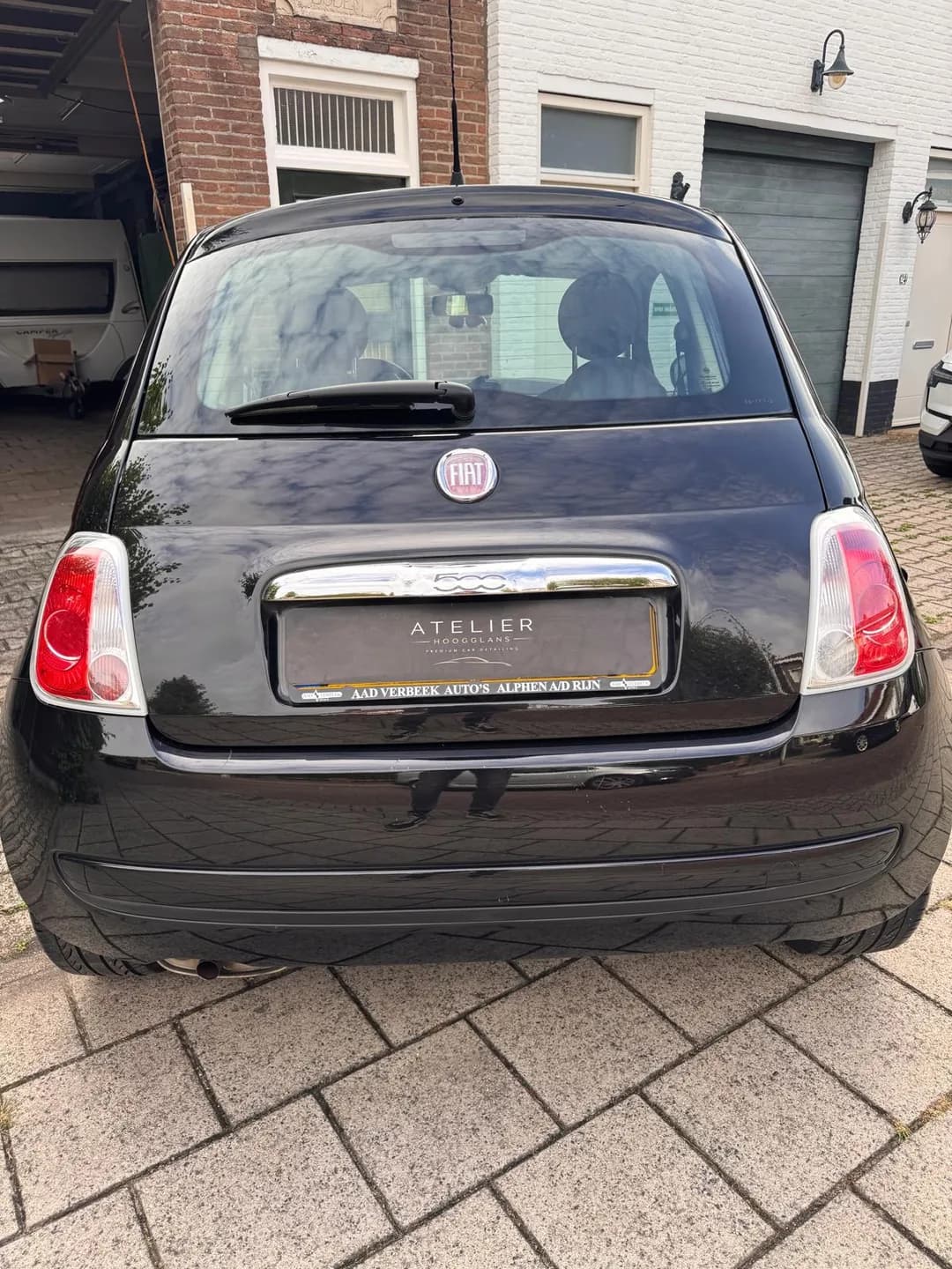Achterzijde van de zwarte Fiat 500 met chromen handgreep en Atelier Hoogglans kentekenafdekking