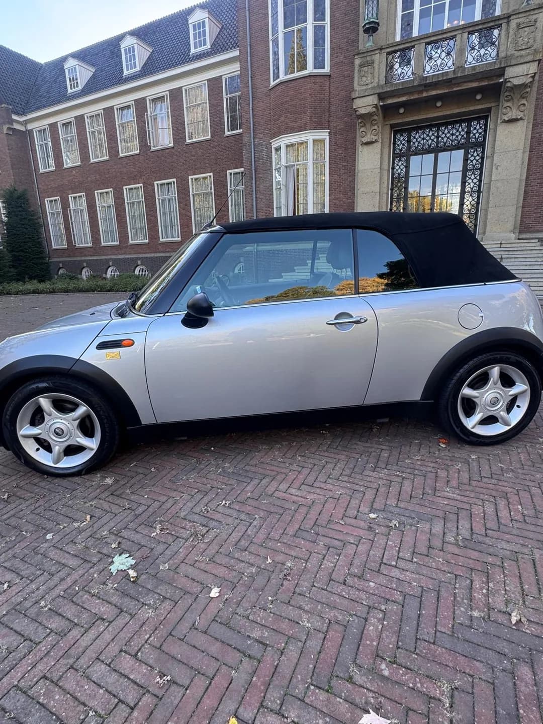 Zilveren MINI Cabrio in zijaanzicht met zwarte gesloten stoffen kap