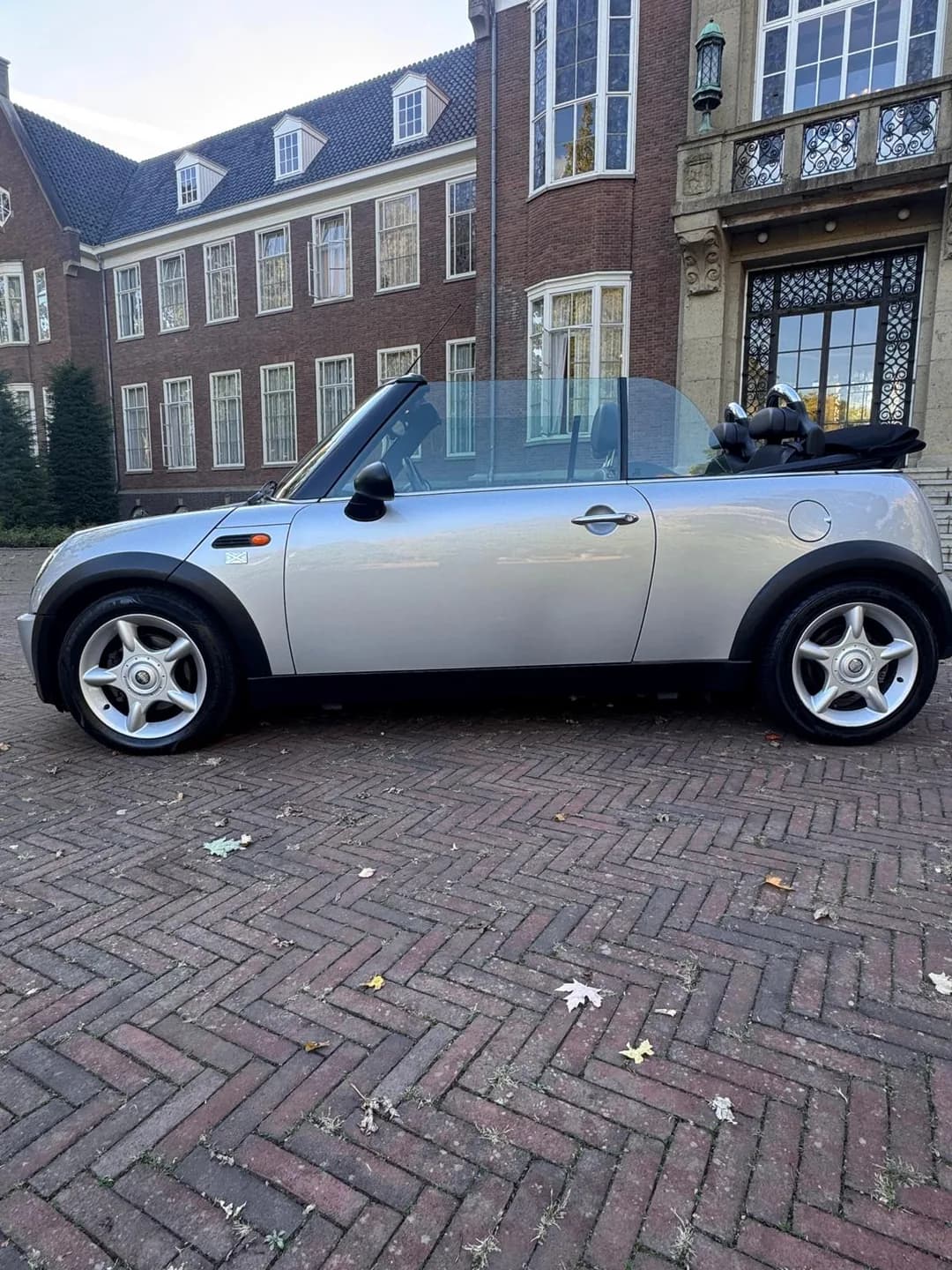 Zilveren MINI Cabrio in zijaanzicht met geopend dak