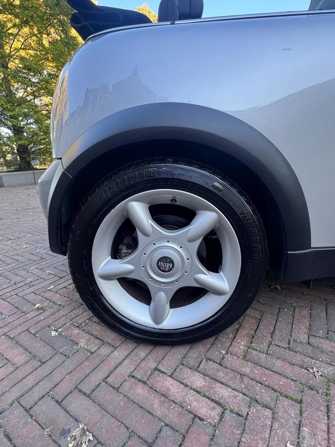 Achterwiel van de zilveren MINI Cabrio met vijfspaaks velg en zwarte wielrand